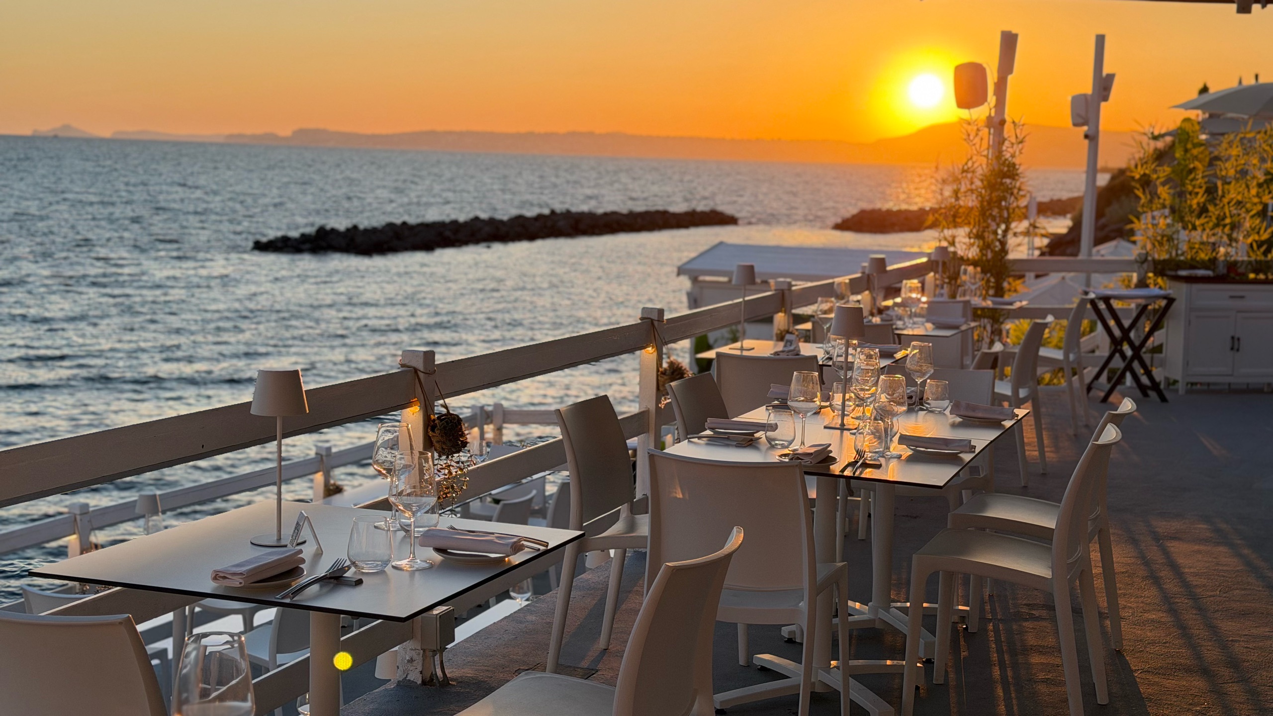 La terrazza del lido con i tavoli apparecchiati al tramonto sul mare di Torre del Greco